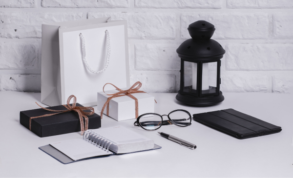 a-paper-bag-two-gift-boxes-notebook-pen-glasses-and-lamp-on-top-of-a-table