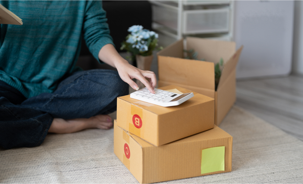 a-hand-using-a-calculator-placed-on-top-of-a-box