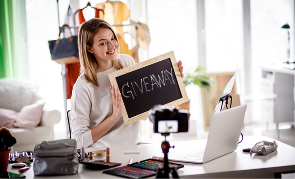 a-woman-holding-a-mini-board-with-words-written-giveaway