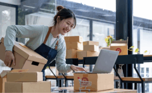 A-woman-using-a-laptop-while-holding-a-box